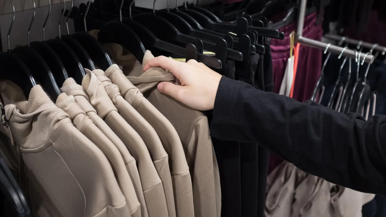 Egy lány pulóvereket nézeget egy ruhaboltban az őszi ruhatára felfrissítése céljából
