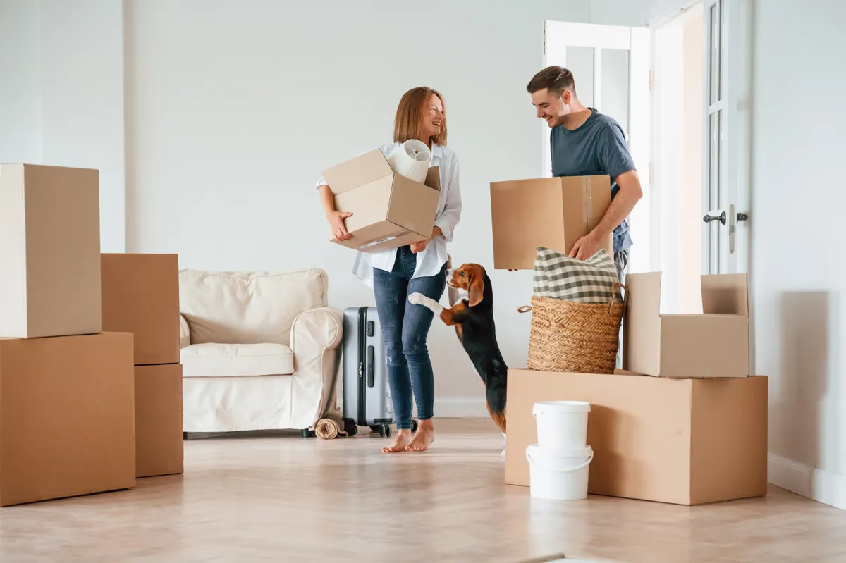 Two,Boxes,In,Hands.,Young,Couple,With,Dog,Are,Moving