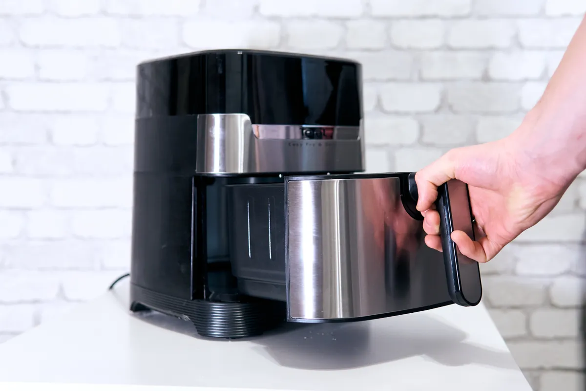 Egy férfi kihúzza az airfryer kosarát