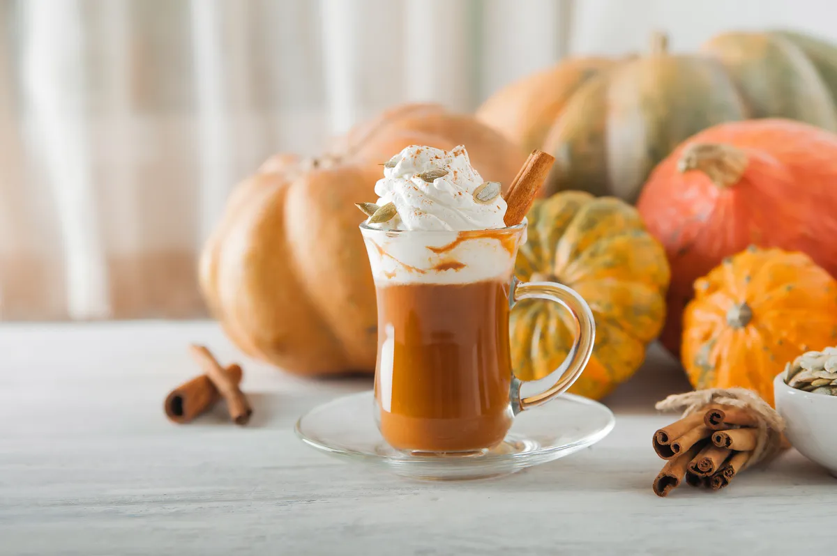 Egy csésze sütőtökös latte dísztökök előtt