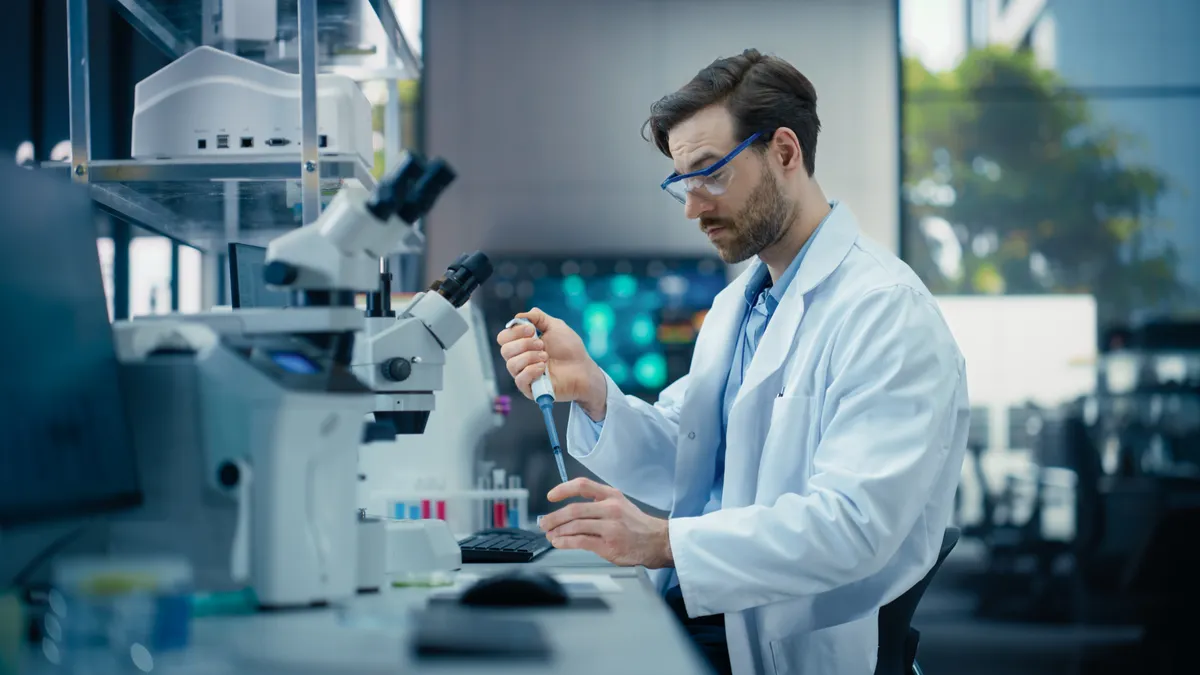 A krónikus fáradtság okait kutató laboráns egy laboratóriumban, pipettával a kezében