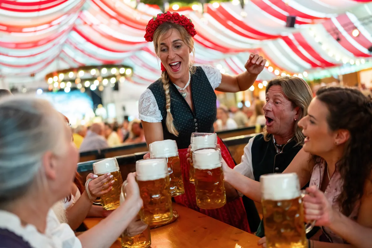Dirndlbe öltözött nő sörrel koccint az Oktoberfesten