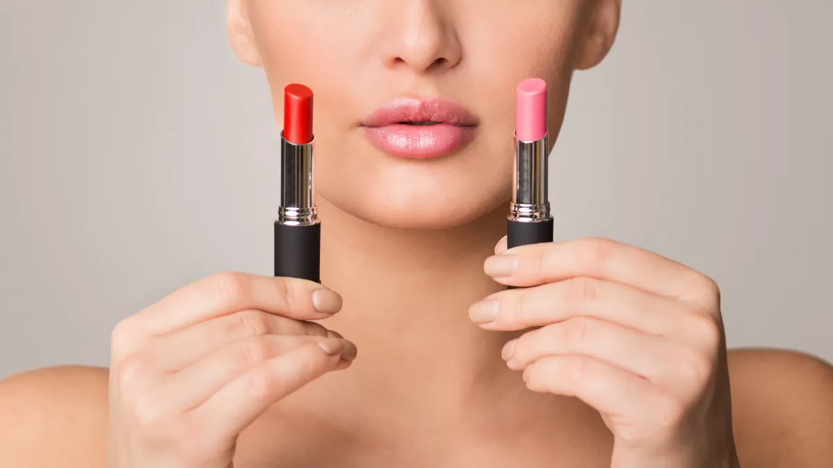 Nő két különböző színű rúzst tart a kezében.