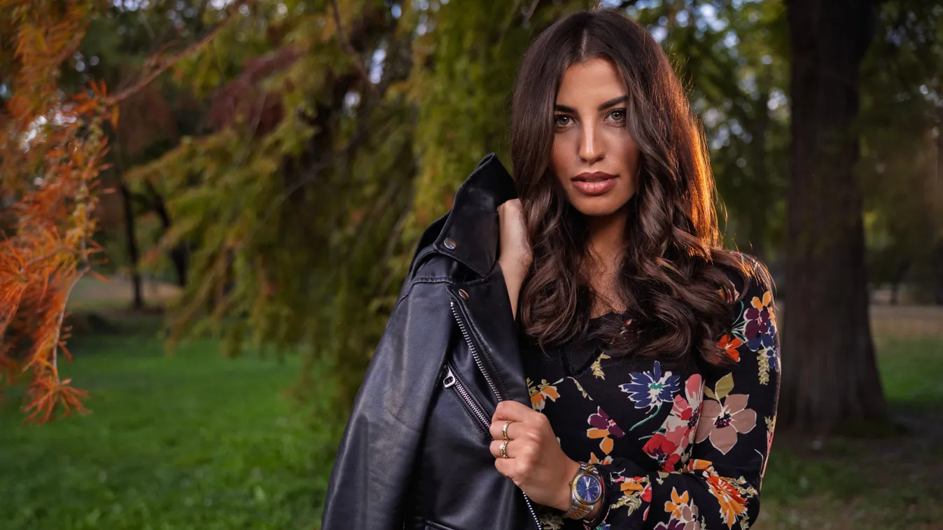 Fiatal modell virágos ruhában és bőrdzsekiben egy parkban