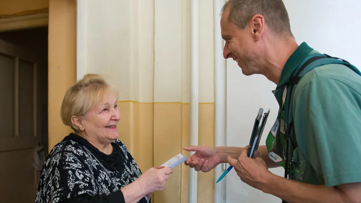 Nyugdíjas utalványt kézbesít a postás.