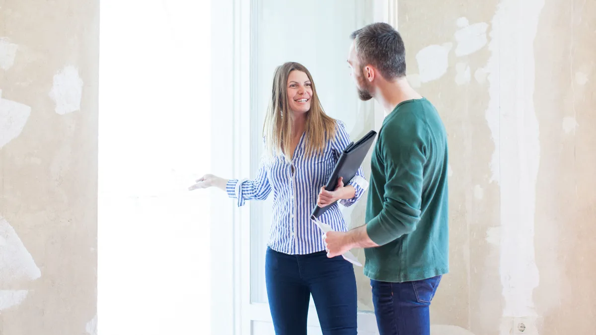 Ingatlanközvetítő lakást mutat egy érdeklődőnek, aki felkészült az ingatlanközvetítői átverések ellen