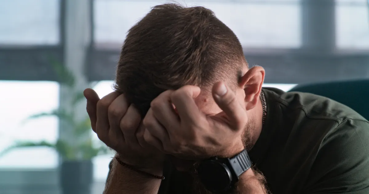 Magas kortizolszint miatt stresszes férfi a kezeibe temeti az arcát