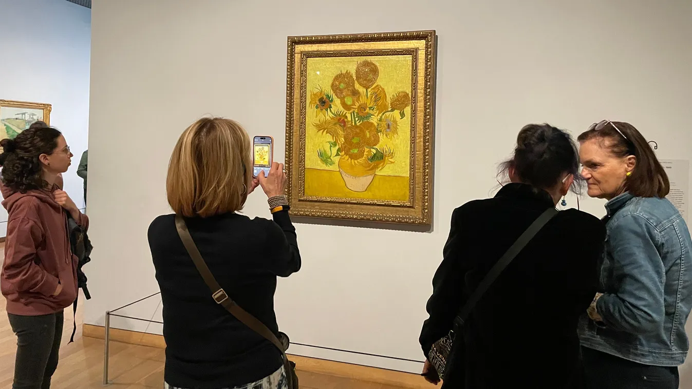 Művészeti galériában műveltségei kvízhez festményt fotózó hölgy