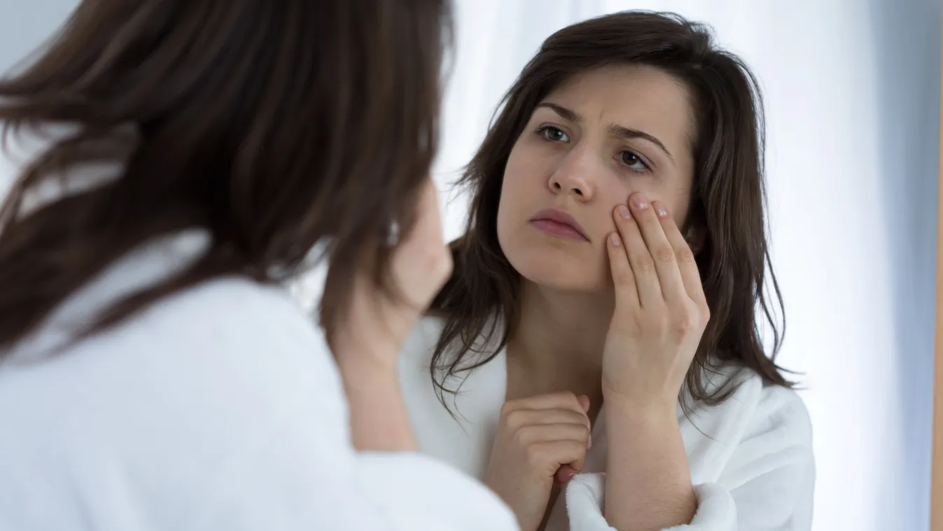 Egy nő a szemét vizsgálja a tükörben