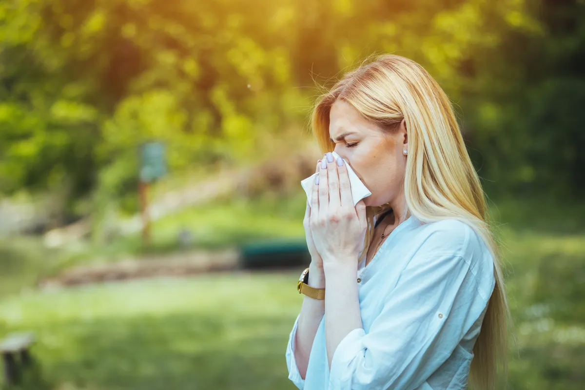 allergiás asztma tüneteitől szenvedő nő orrfújás közben