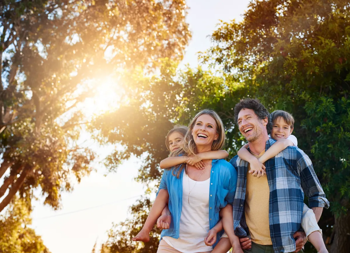 Family,,Laughing,And,Piggyback,In,Park,With,Love,For,Bonding,