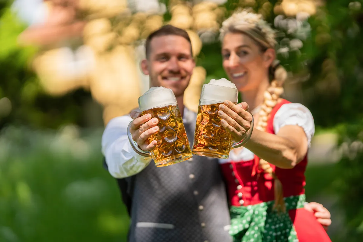 Tradicionális ruhába öltözött pár az Oktoberfesten sörrel a kezében