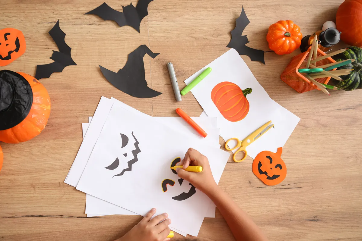 Papírokból halloweeni dekorációt készítő gyerek