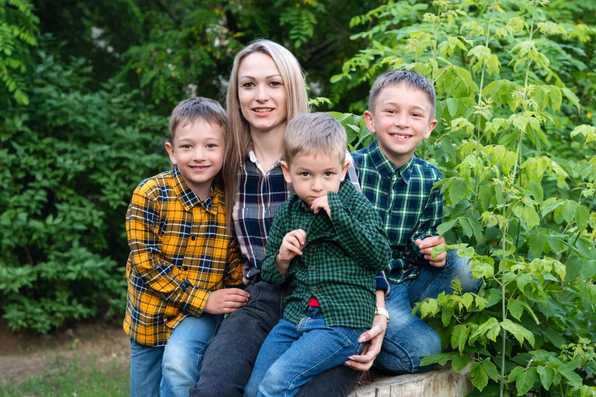 Single,Parent,Family,With,Three,Children,Sitting,On,Tree,Stumpand