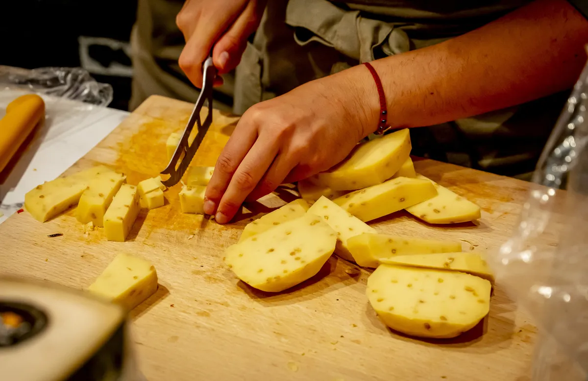 Érlelt sajtokat kockázó nő