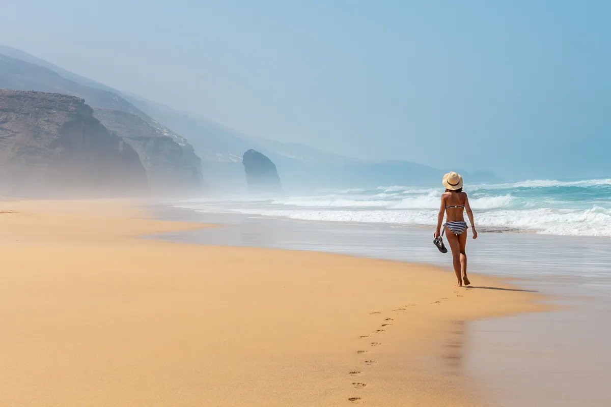 Kanári-szigetek, Fuerteventura érintetlen partvidéke egy strandon sétáló nővel