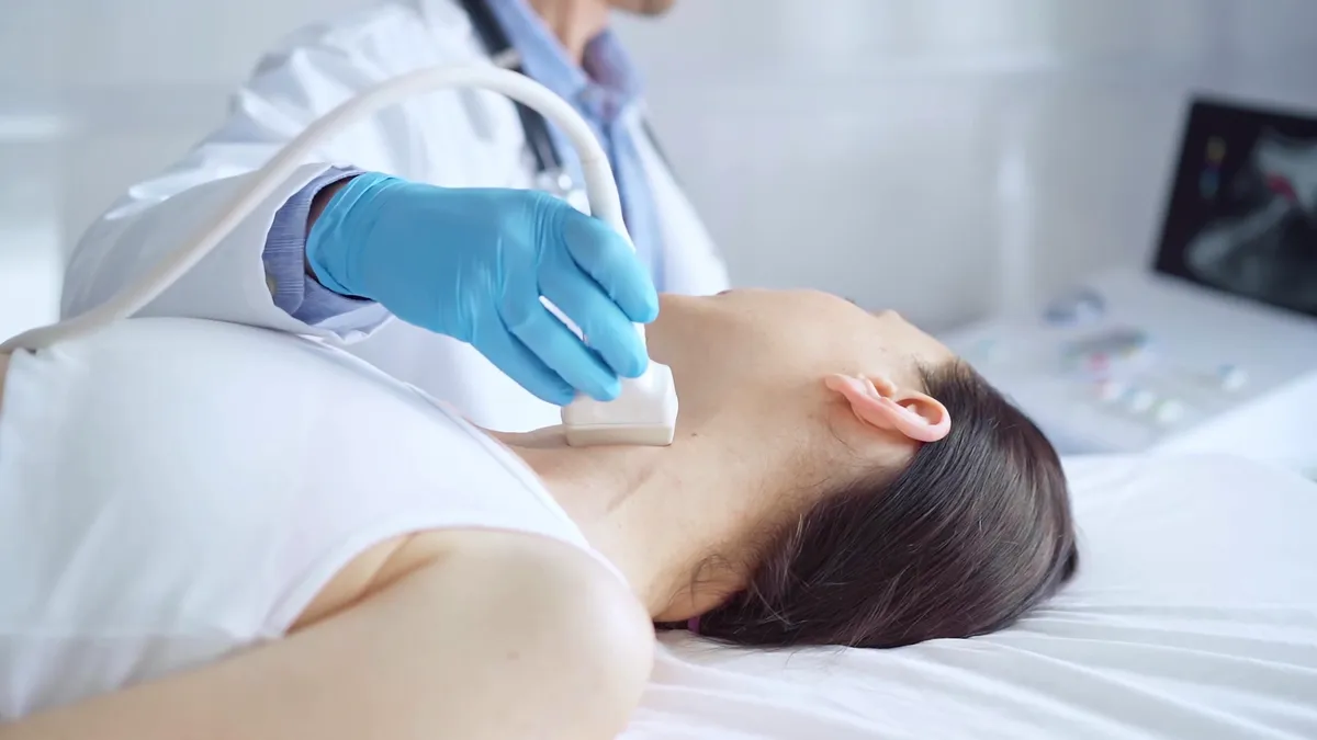 Ultrahangos pajzsmirigyvizsgálaton részt vevő nő egy ágyon fekve