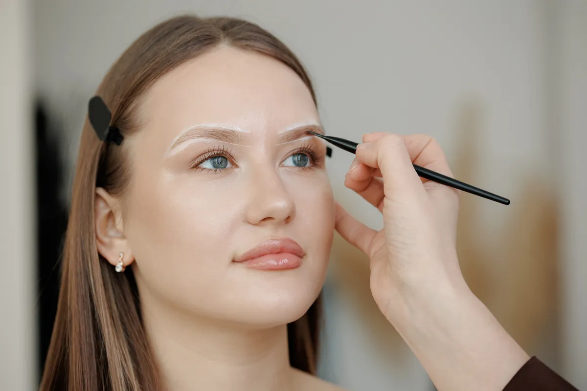 Egy sminket szemöldökceruzával húzza ki egy fiatal modell szemöldökét