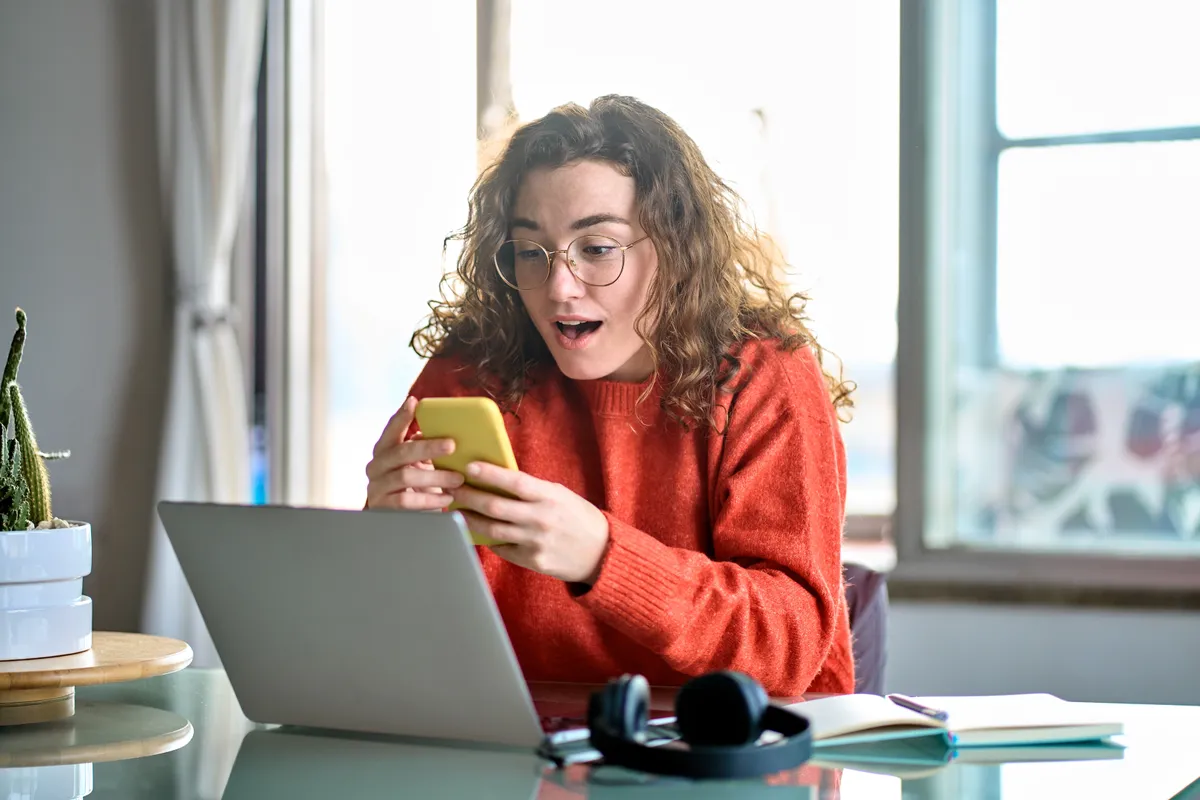 látás javítása telefon- és laptopképernyőt néző nő.