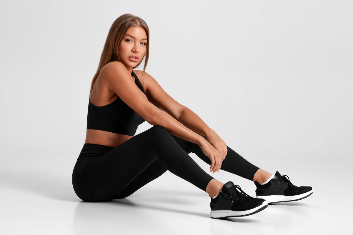 Egy leggingsben és sportcipőben a földön ülő nő