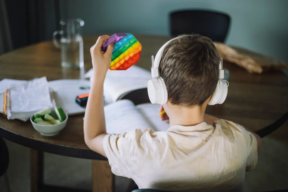 Autizmussal élő gyerek fejhallgatóval a fején ír és játszik