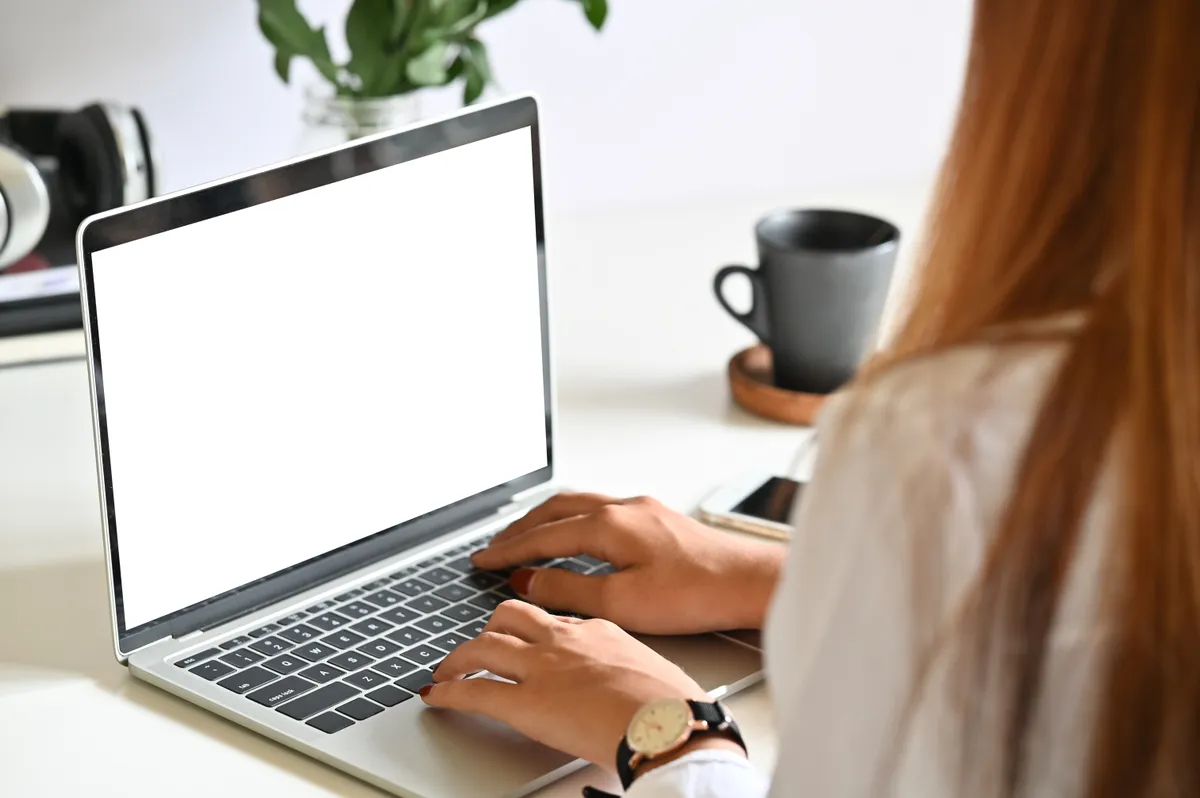 Spórolási tippek: fiatal nő ül egy laptopot előtt az asztalnl.