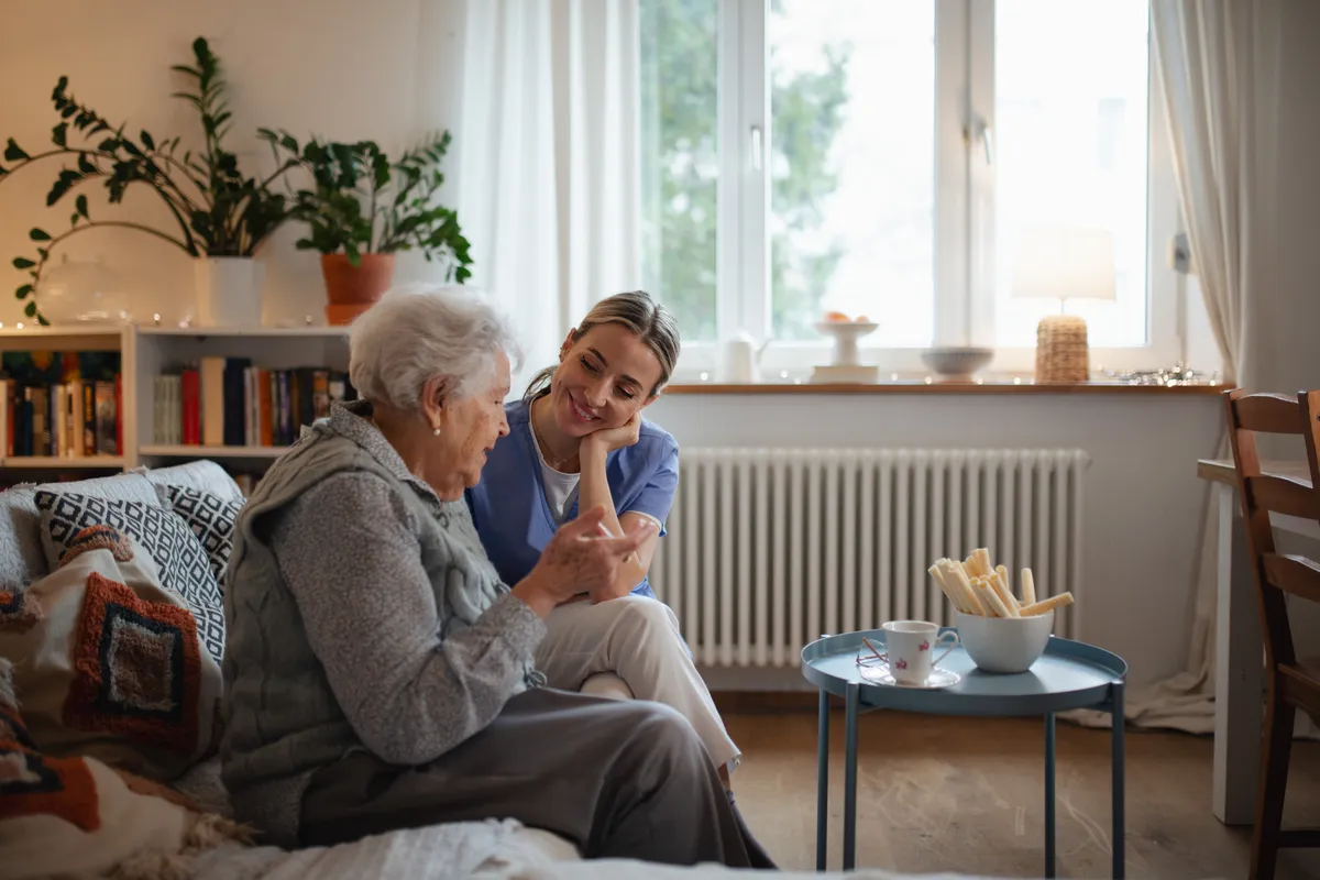 Alzheimer-kóros idős nénivel ül egy ápolónő az otthonában