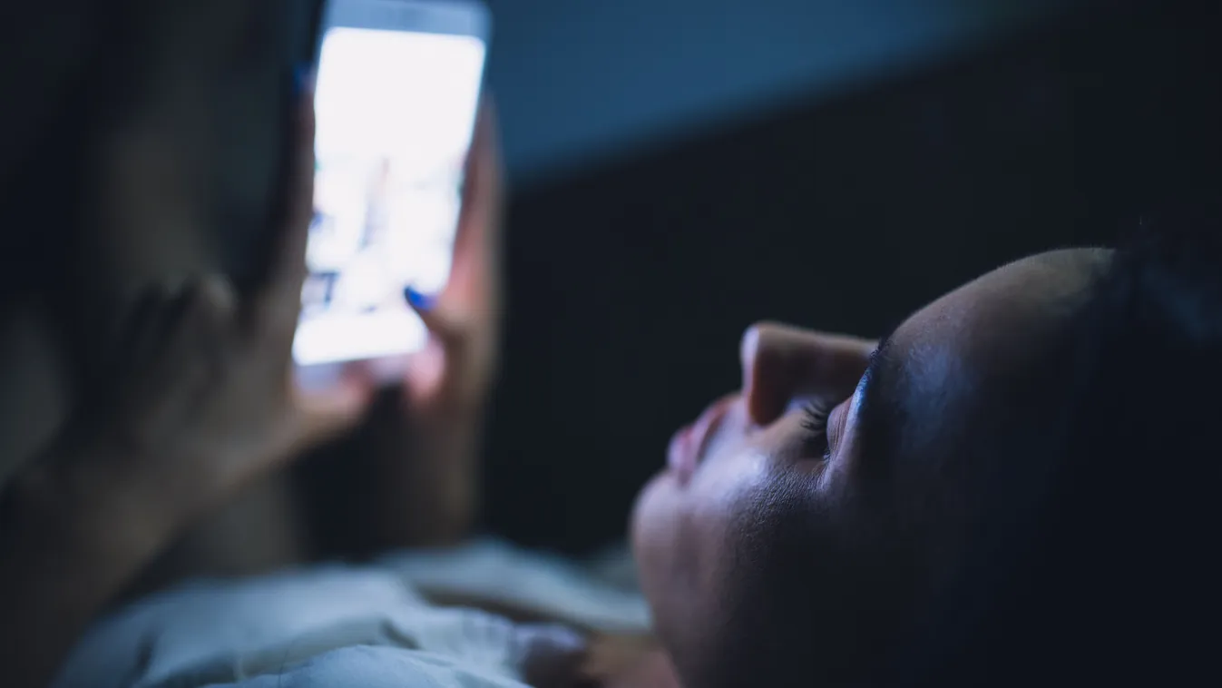 Alvás előtt okostelefonozó nő az ágyban