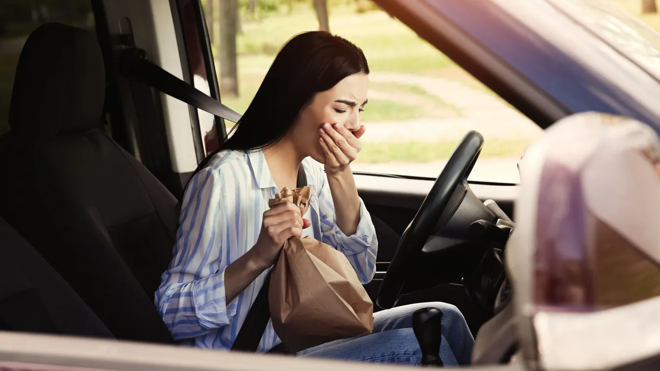 Hányingerrel küzdő nő egy autó volánja mögött