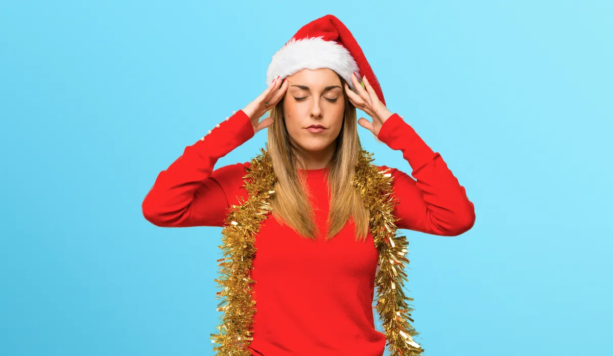 Egy nő akinek fáj a feje a karácsonyi daloktól.