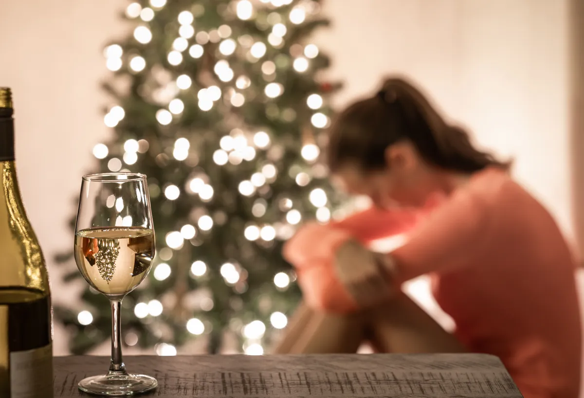 Egy nő a szilveszteri szomorúságtól magába roskadva ül a karácsonyfa alatt.