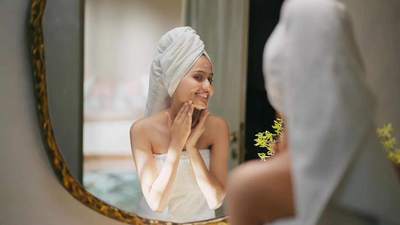 Otthoni kényeztető szépségpraktikát alkalmazó fiatal nő a tükör előtt