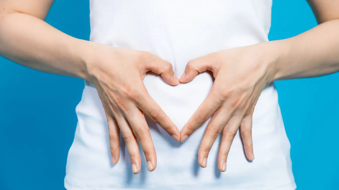 A mikrobiom szeretetét a hasa előtt ujjakból formált szív alakkal jelző nő