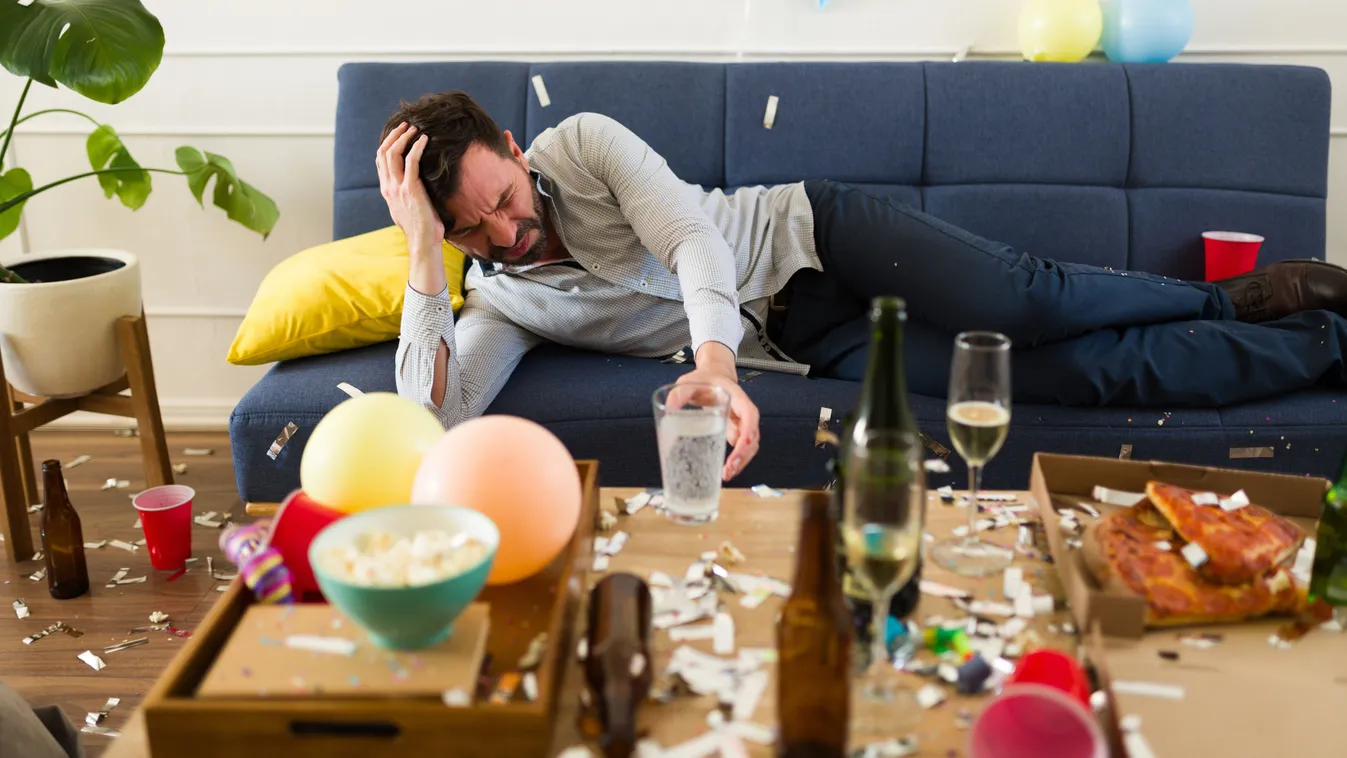 Másnaposság ellen egy pohár vízért nyúló férfi