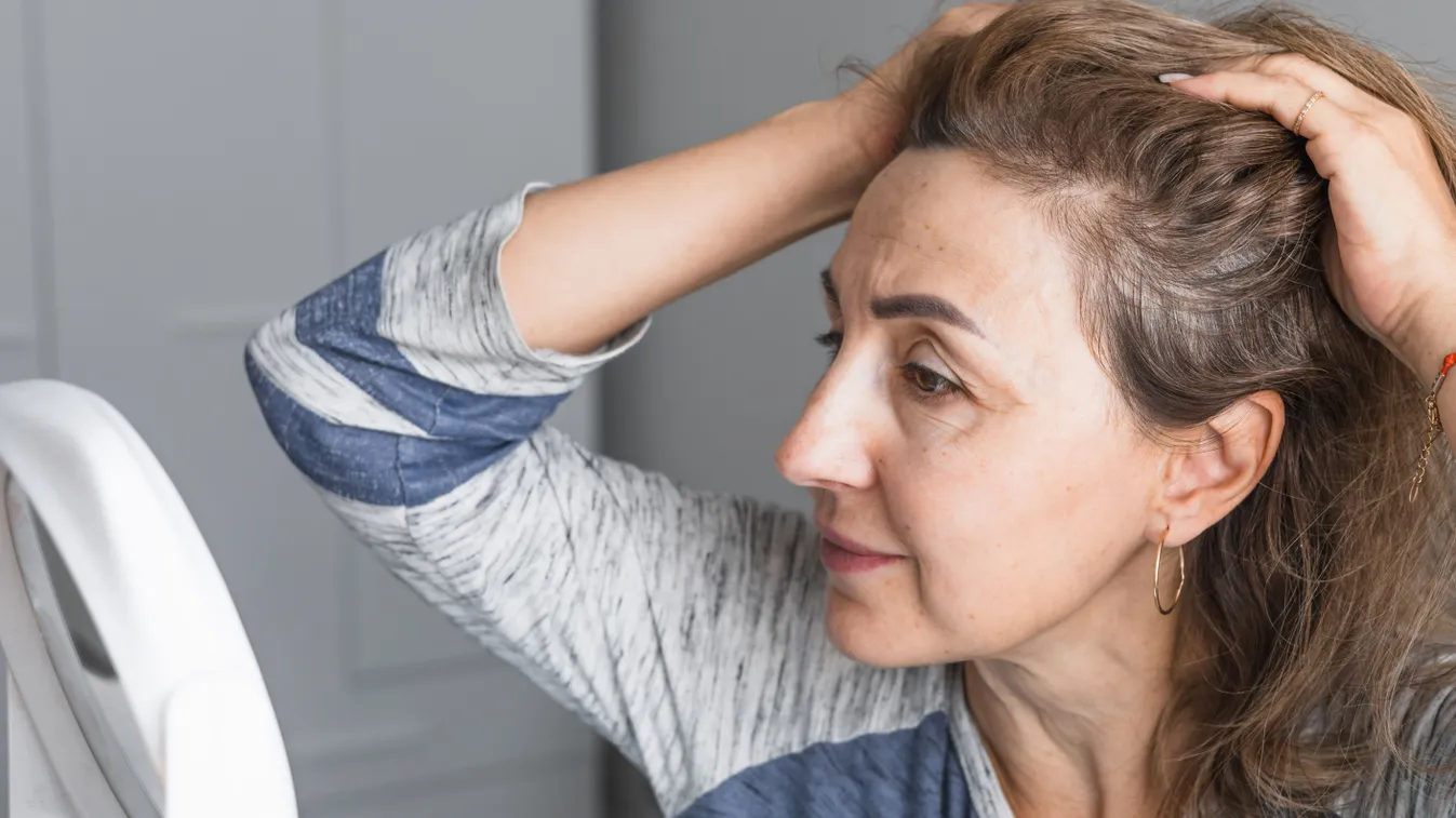 Tükörben arcdiagnosztikát végző felnőtt nő