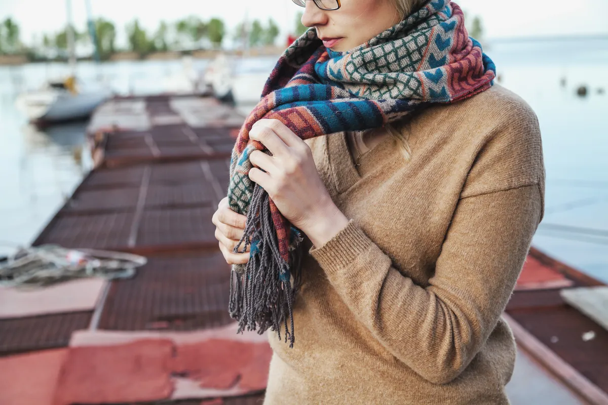 Fiatal lány színes sálat köt a nyakára