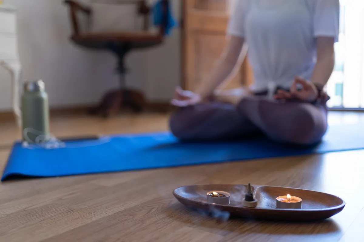 Egy nő aki meg akar szabadulni az átoktól  gyertyát és füstölőt gyújtott és közben meditál