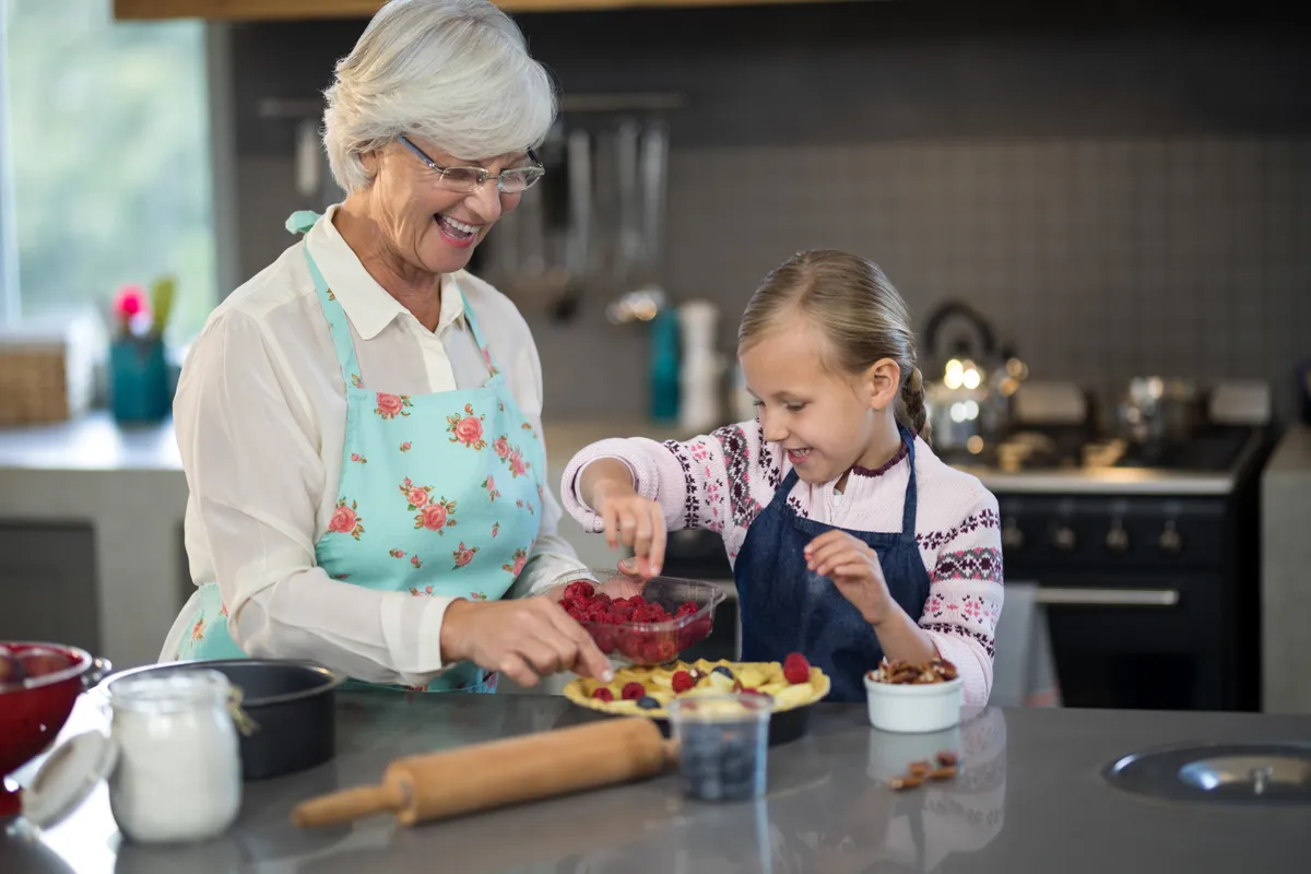 Unokájával sütit sütő nagyszülő a konyhában