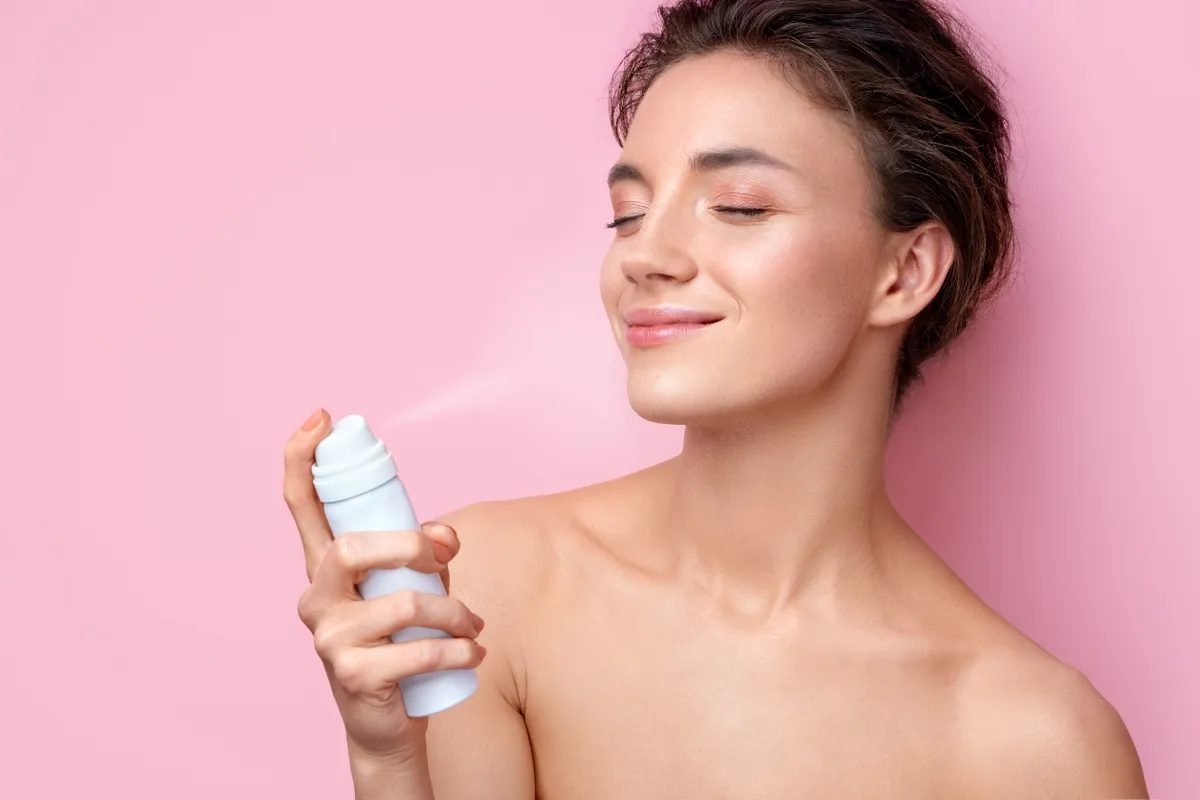 Frissítő permetet alkalmaz egy nő fáradt arcra