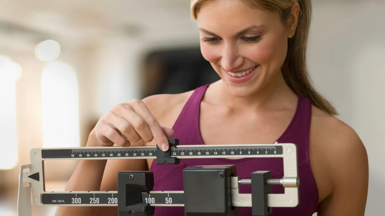 A súlyát mérő boldog nő, akinek sikerült elérnie a tartós fogyást.