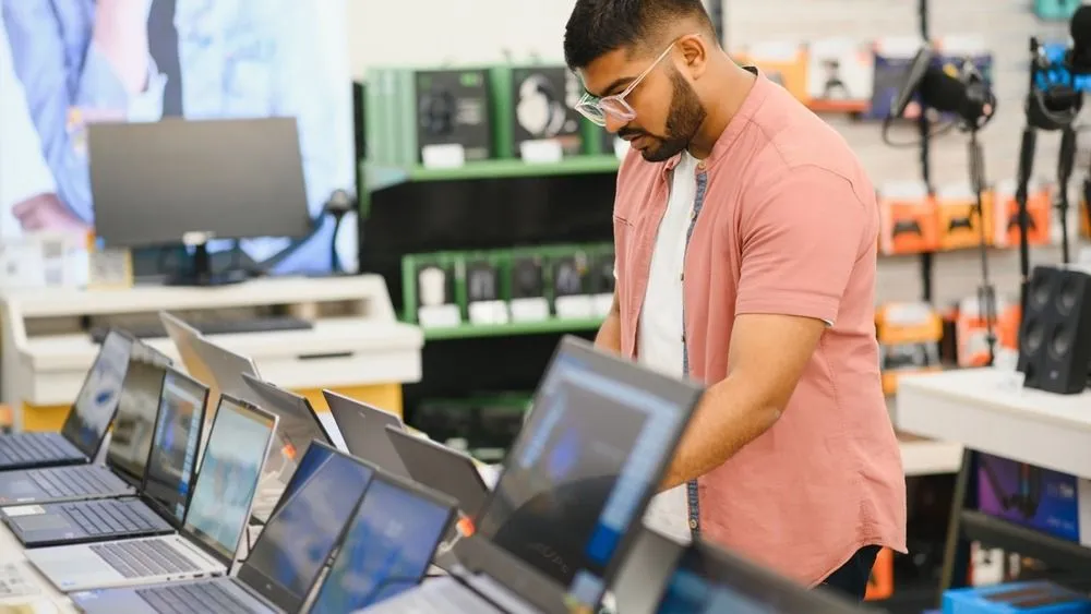 A,Young,Man,Stands,Behind,His,Laptop,At,The,Electronics