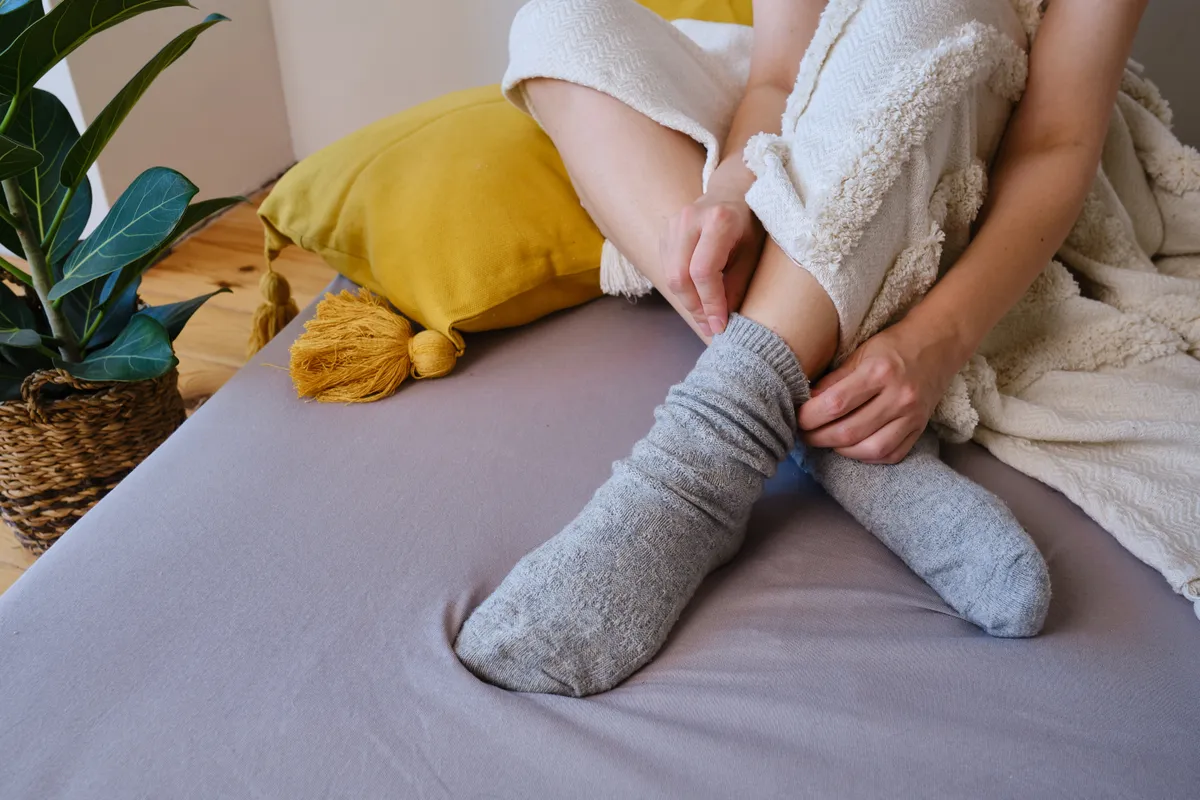 Gyapjúzoknit visel egy nő a hideg lábak ellen