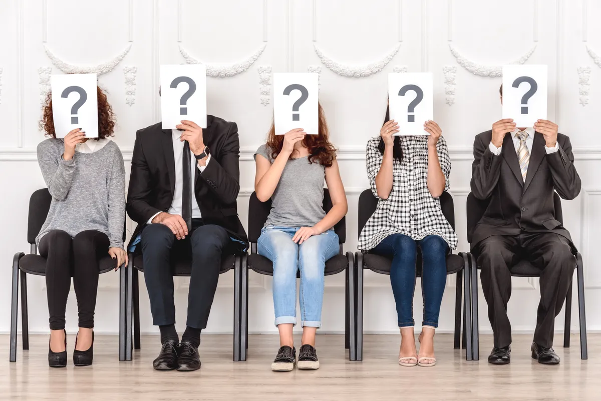 5 ember akik részt vesznek a kvíz kitöltésében eltakarják az arcukat kérdőjelet ábrázoló lappokkal