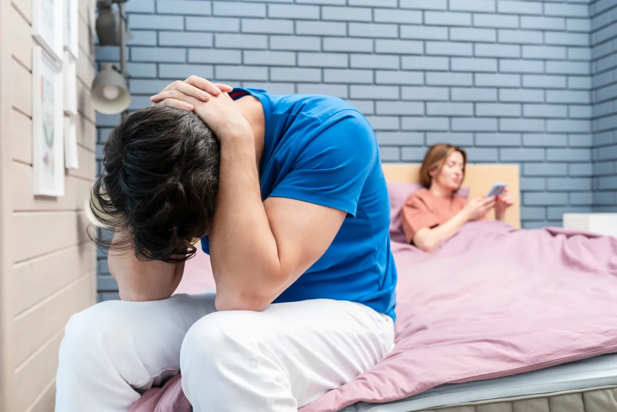 merevedési zavar miatt kiborult férfi ül az ágy szélén.