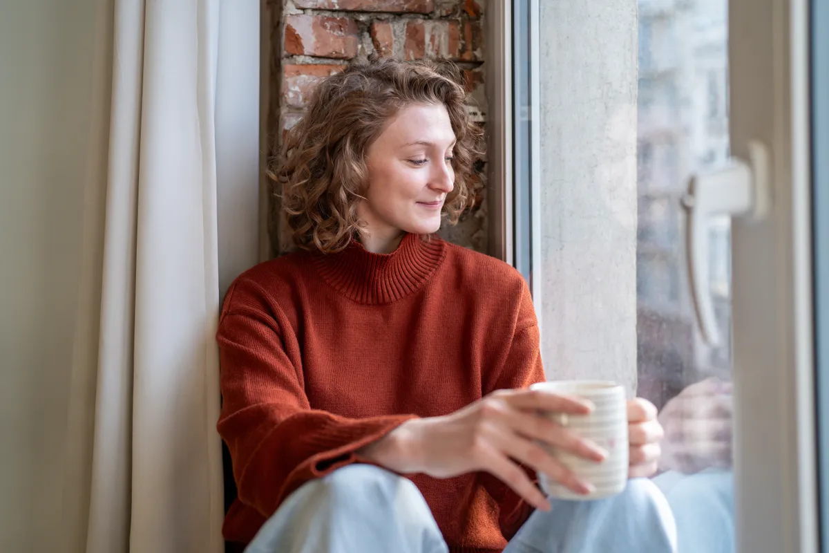 Vérnyomáscsökkentő diéta közben ablakban megpihenő fiatal nő