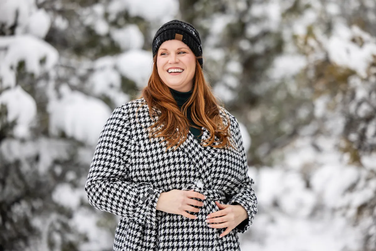 Stílusos téli szettet viselő nő a havas tájon.