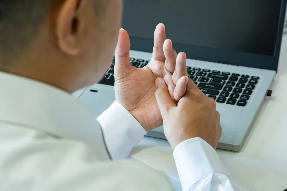 Ínhüvelygyulladással küzdő irodai dolgozó egy laptop előtt