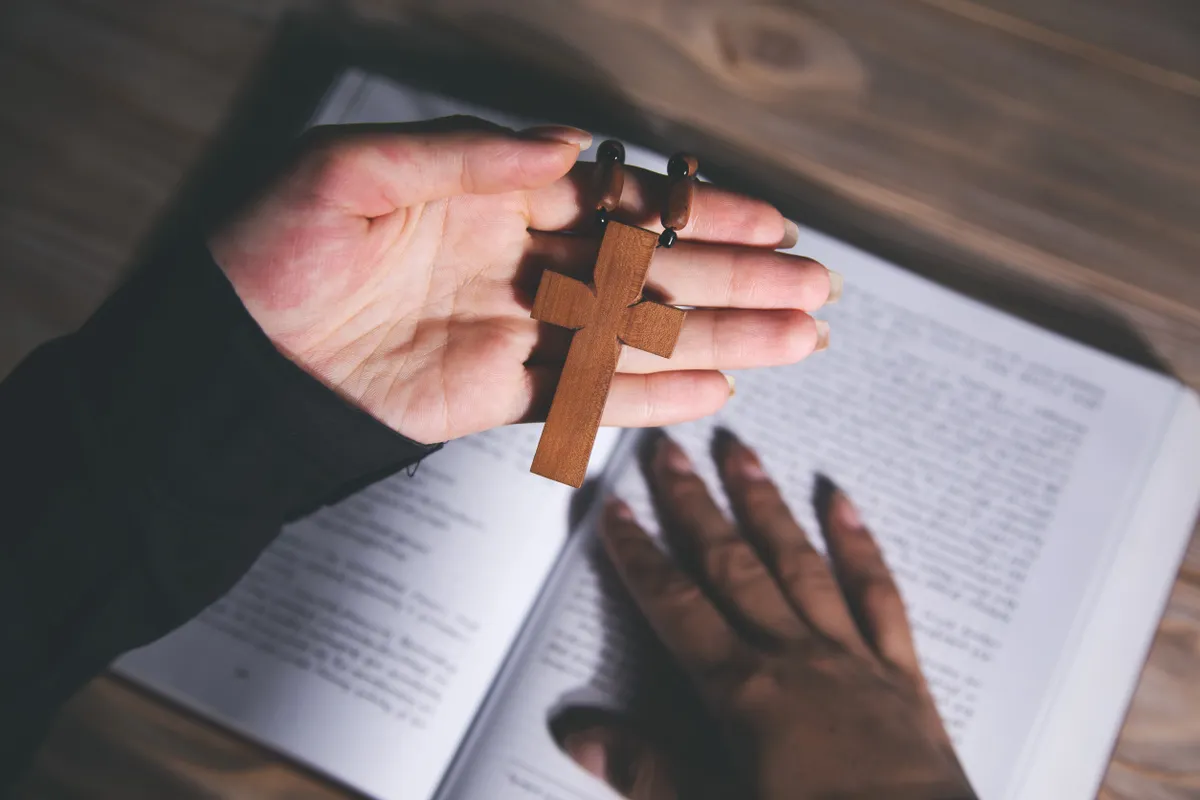 Egy pap egyik kezében egy kereszt másik a Biblián épp ördögűzésre készül