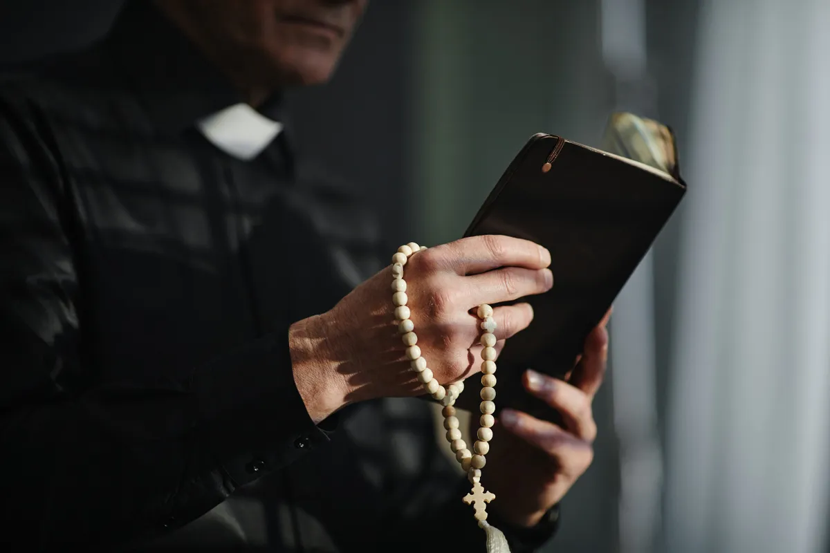 Egy pap kezében rózsafüzér és egy Biblia ördögűzésre készül