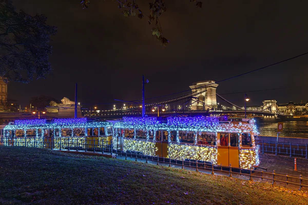 Fényvillamos közlekedik Budapesten, háttérben a Lánchíddal